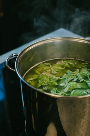 A pot with Italian spinach pasta cooking on the stove. Steam over the pot. Close up.