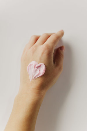 Woman's hand with a smear of cream in the shape of a heart. Skin care beauty product. Cosmetology...