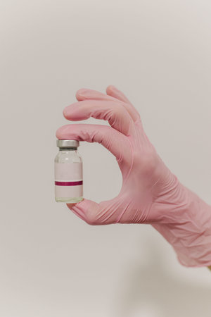 Cosmetologist in pink glove holding ampoule at cosmetology clinic. Close up. Cosmetology concept.