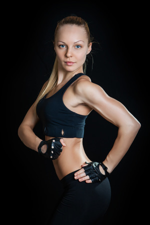 Athletic young woman showing muscles arms on a isolated black backgroundの写真素材