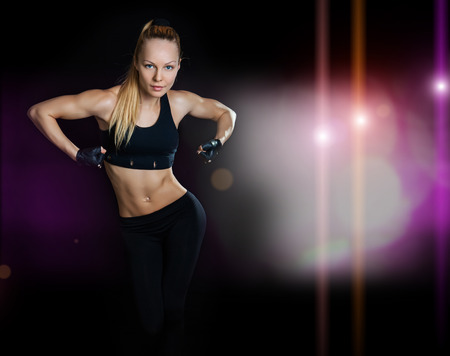 Athletic young woman showing muscles arms on a isolated black backgroundの写真素材