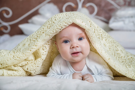 baby looking out from under blanketの写真素材