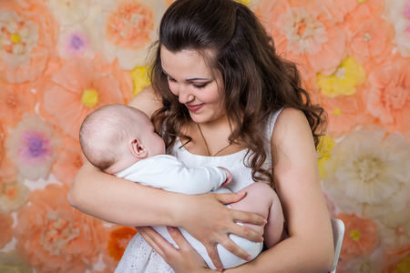 young woman holding a baby on a floral background
