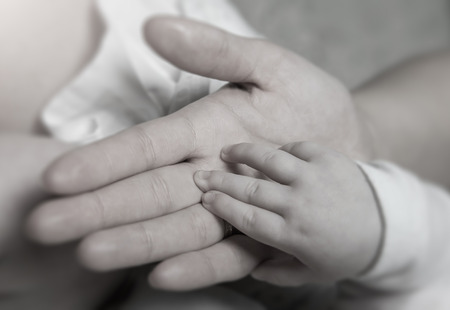Female hand holding newborn baby's hand, black and white tonedの写真素材