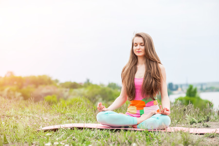 Peaceful healthy & fit young woman meditating on the nature with eyes closedの写真素材