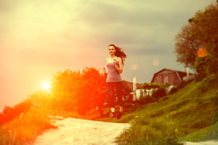 a woman jogging in sunny bright light outside cityの写真素材