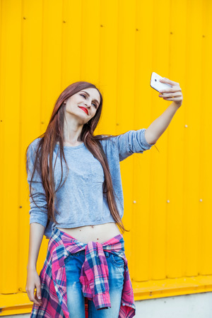 Outdoor portrait of beautiful girl taking a selfie with mobile phone in cityの写真素材