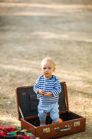 Happy infant baby toddler staying in old vintage travel suitcase outdoorの写真素材