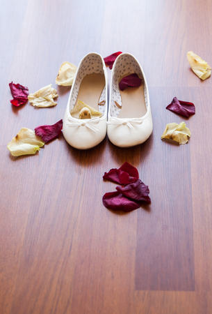Bridal shoes lie on the floor, scattered rose petals, in the light of the sunの写真素材
