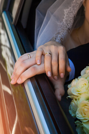 hands of the bride and groom and wedding bouquet on black box carの写真素材