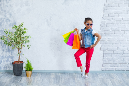 cute African girl with shopping bags Against the gray wallの写真素材