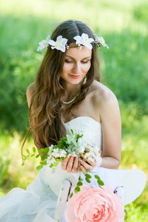 Beautiful happy bride in a white dress in the garden, with flowers.の写真素材