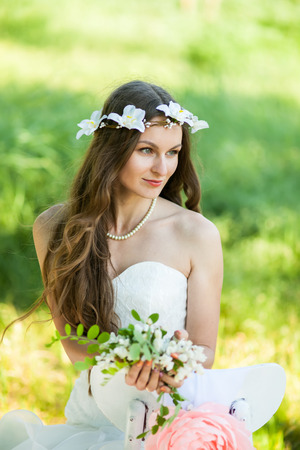 Beautiful happy bride in a white dress in the garden, with flowers.の写真素材