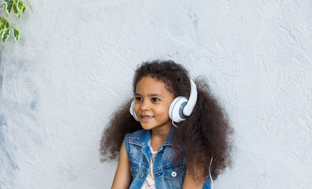 cute African girl listening to music in big white headphones の写真素材