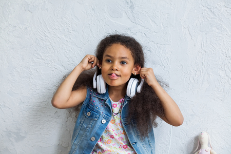cute African girl listening to music in big white headphonesの写真素材