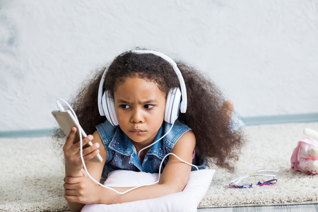 cute African girl at home, listening to music in big white headphonesの写真素材