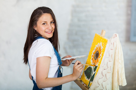 Getting creative. Woman artist painting a sunflower at homeの写真素材