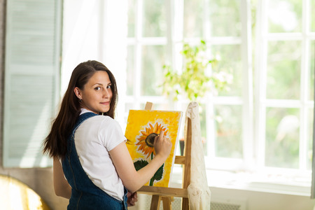 Getting creative. Woman artist painting a sunflower at homeの写真素材