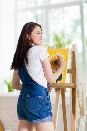 Getting creative. Woman artist painting a sunflower at homeの写真素材