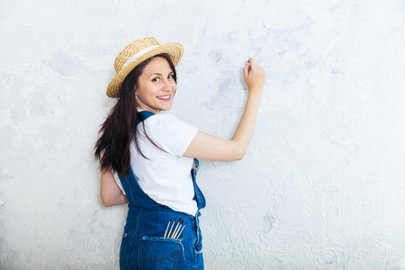 Happy female artist in a straw painting the grey wallの写真素材