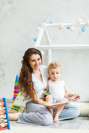 Mother with child playing educational toys and reading book in the roomの写真素材