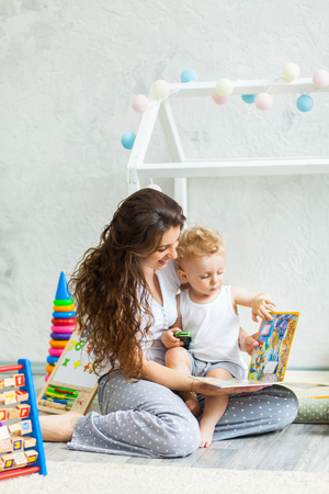 Mother with child playing educational toys and reading book in the roomの写真素材