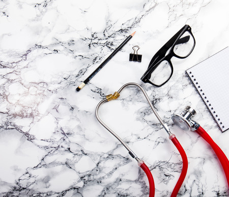 mininmal monochrome doctors office table desk workspace with diary plant stethoscope glasses keyboard pencil on black and white tableの写真素材