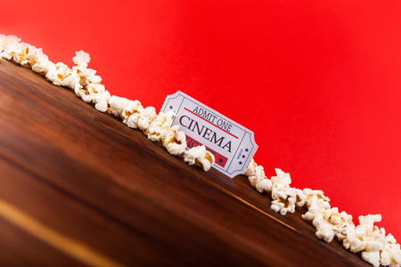Cinema background. Film watching. Popcorn and tickets on the wooden and red background copy spaceの写真素材