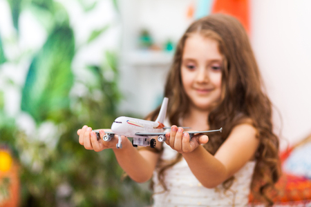 Charming little girl in cute arabic interior is holding an airplane. Travel concept.の写真素材