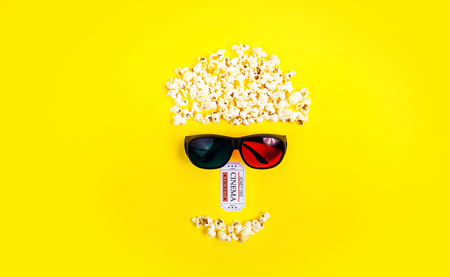 Abstract image of viewer, 3D glasses and popcorn, text "movie" on yellow background. Still life, top view, flat lay. Concept cinema and entertainmentの写真素材