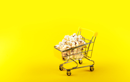 Popcorn in a shopping trolley on pink background top viewの写真素材