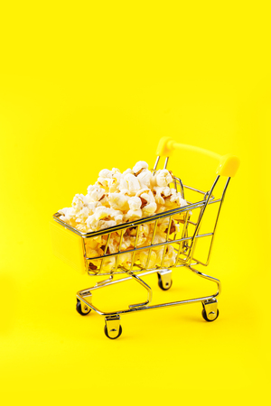 Popcorn in a shopping trolley on pink background top viewの写真素材