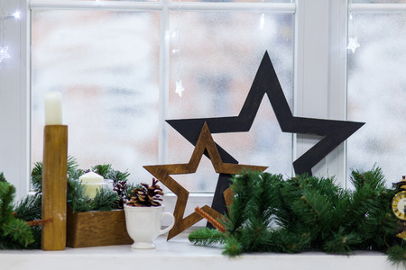 Vintage Christmas background with Christmas decoration against winter window, wooden stars, candle,...
