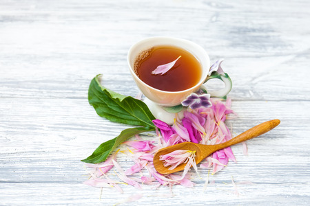 Cup of green tea and spring peonies blossom on a old wooden background. Rustic.の写真素材