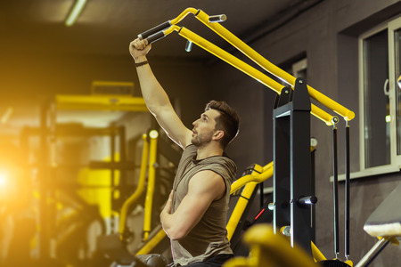 Concept Power Strength Healthy Lifestyle Sport Powerful Muscular man working out in gym doing exercises at on traction on training machineの写真素材