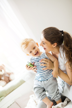Young mother kissing her baby lying on the bedの写真素材
