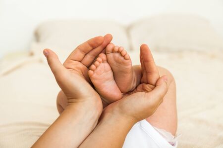 Baby's feet in mother hands. Mom and her Child. Happy Family concept. Beautiful conceptual image of...