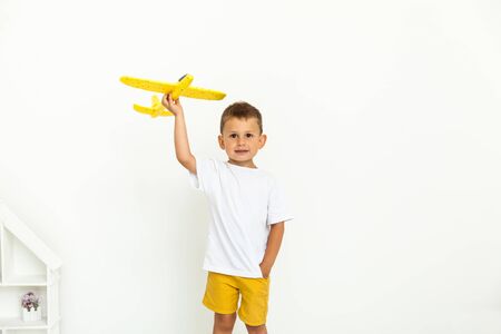 Happy cute child toddler playing with yellow toy airplane and dreaming of becoming a pilotの写真素材