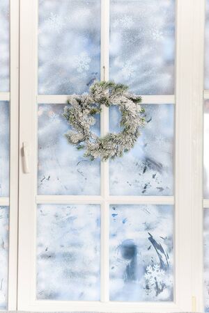 Frosted window with festive Christmas wreath and holiday decorationsの写真素材