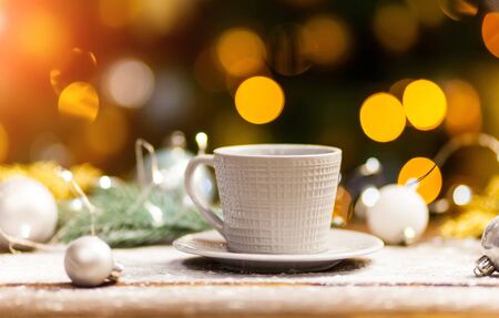 White coffee mug with gold shiny Christmas decorations. Space for text or design. Christmas backgound with bokehの写真素材