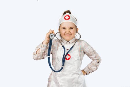 Happy girl playing a doctor - over a pink backgroundの写真素材
