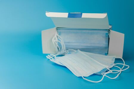 Surgical protective mask. Box of Medical respiratory bandage face Shortage of masks on a blue background. prevention of the spread of virus and pandemic COVID-19.の写真素材