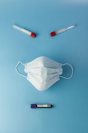 Protective mask and blood sample tubes in the shape of a monster face. Virus danger concept on a...
