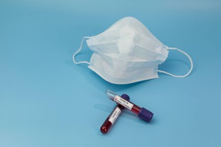 Protective mask and blood sample tube on a Blue background. Novel coronavirus 2019 nCoV. The...