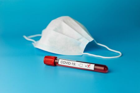 Protective mask and blood sample tube on a Blue background. Novel coronavirus 2019 nCoV. The inscription Stop Coronavirus.の写真素材