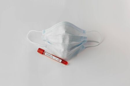 Protective mask and blood sample tube on a White background. Novel coronavirus 2019 nCoV. The...