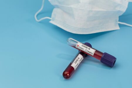 Protective mask and blood sample tube on a Blue background. Novel coronavirus 2019 nCoV. The...