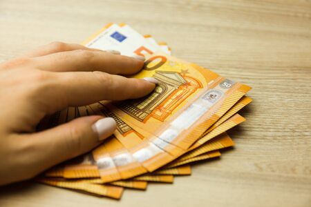 Fan of 50 euro banknotes. Fan of 50 euro banknotes on the wooden background. Financial crime, dirty money and corruption concept.の写真素材