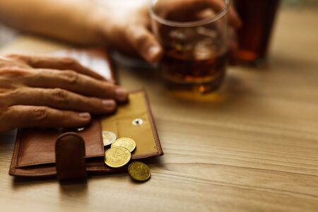 Fired man countsing his last money to drink expensive alcohol. Wrinkled alcoholic sits at brown...