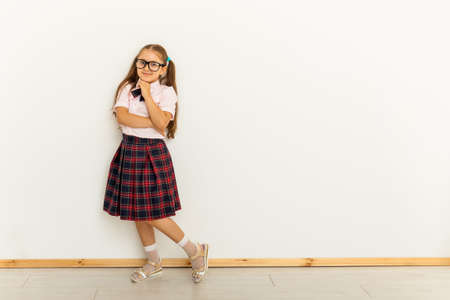 Full body size length of thinking girl with with two tails, in formal blouse shirt, red plaid skirt over white backgroundの写真素材